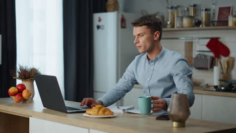 Man-working-laptop-kitchen-with-fresh-coffee.-Businessman-searching-information.