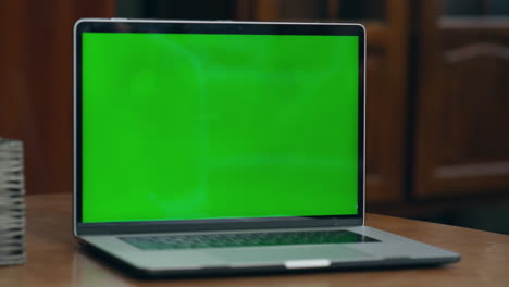 Woman-hand-turn-on-green-mock-up-screen-on-modern-laptop-indoor-close-up.
