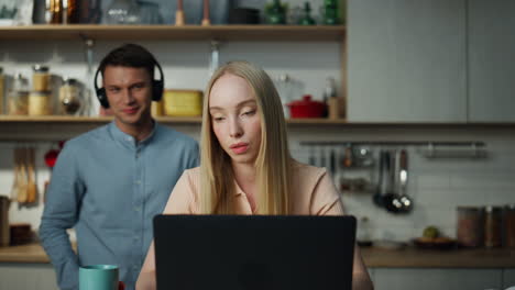 Businesswoman-surfing-internet-laptop-on-laptop.-Man-listening-music-on-backdrop