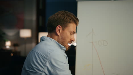 Active-man-drawing-whiteboard-at-remote-office.-Specialist-explaining-plan