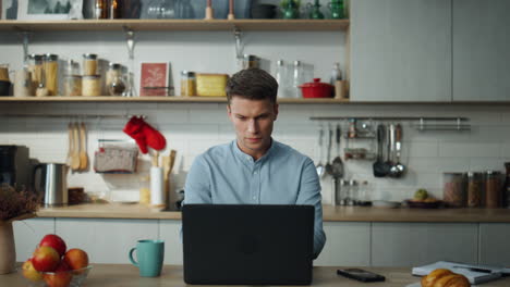 Business-man-opening-laptop-starting-work-at-home-kitchen.-Freelance-worker.