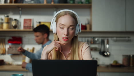 Girl-coach-speaking-video-conference-at-kitchen-with-headphones.-Guy-dancing.