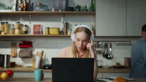 Woman-accountant-working-remotely-sitting-at-kitchen-with-headphones-close-up.