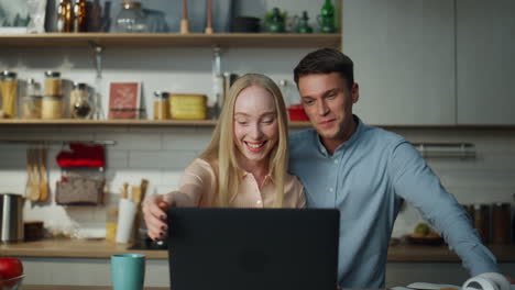 Couple-saying-goodbye-online-meeting-with-friends-at-home-kitchen-close-up.