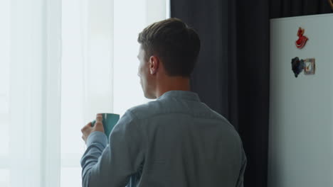 Back-man-drinking-coffee-looking-window-at-morning.-Guy-thinking-about-success.