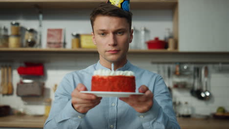 Sad-man-blowing-cake-candle-sitting-alone-at-kitchen-close-up.-Guy-celebrating.