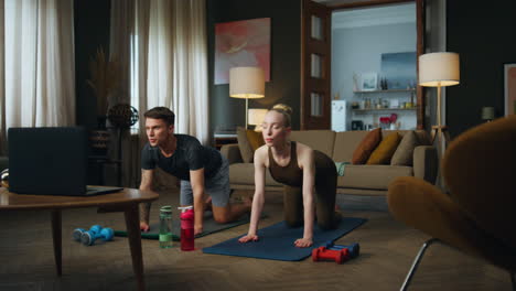 Woman-stretching-body-man-at-home.-Young-couple-standing-on-knees-bending-backs.