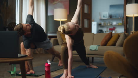 Couple-making-yoga-pose-on-sport-mat-at-home.-Family-practicing-triangle-asana.