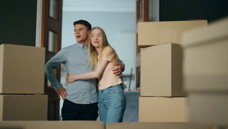 Owners-looking-new-house-full-of-carton-boxes.-Couple-enjoy-buying-modern-flat.
