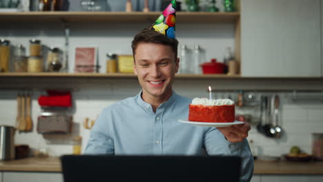 Man-enjoy-virtual-birthday-holding-cake-blowing-candle-closeup.-Guy-celebrating.