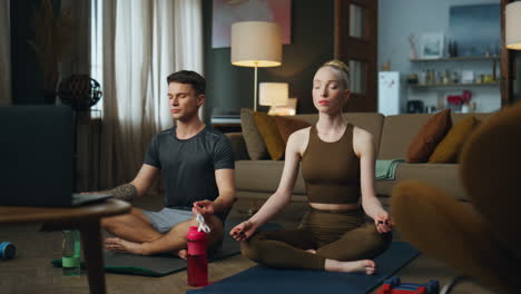 Pareja-Sentada-En-Pose-De-Loto-En-Casa-Practicando-Yoga.-Mujer-Meditando-Con-El-Hombre.