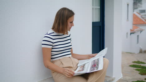 Relaxed-girl-read-newspaper-on-old-town-street.-Carefree-tourist-enjoy-morning