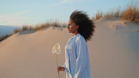 Model-posing-flower-at-sand-dunes-summer-haze-closeup.-Curly-woman-holding-calla