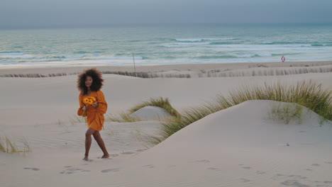 Woman-walking-beach-twilight-with-orange-flowers.-Girl-with-bouquet-on-seashore.