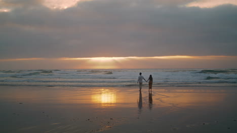 Sweethearts-silhouettes-walking-sunbeams-sea.-People-enjoying-date-vertical-view