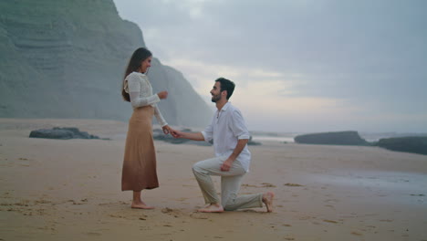 Romantic-man-proposing-marriage-to-woman-at-beach.-Couple-celebrating-engagement