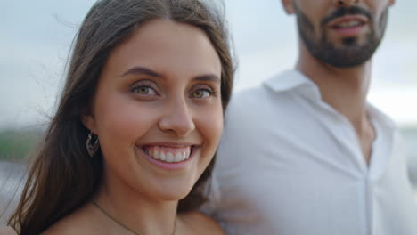 Tender-newlyweds-enjoy-ocean-stormy-beach-closeup.-Woman-face-smiling-camera