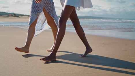 Couple-legs-walking-beach-closeup.-Relaxed-slim-girls-enjoying-going-ocean-shore