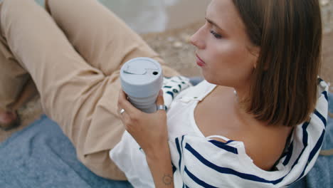 Woman-drinking-picnic-coffee-on-cliff-edge-closeup.-Pensive-girl-rest-seashore