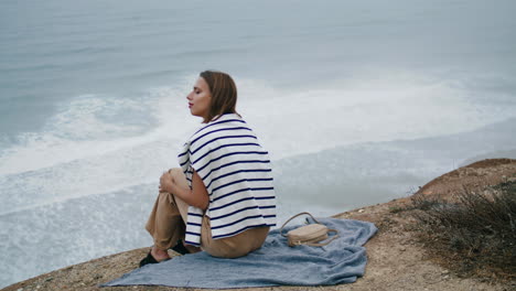 Woman-resting-ocean-cliff-mountain-alone.-Serene-person-enjoying-ocean-landscape