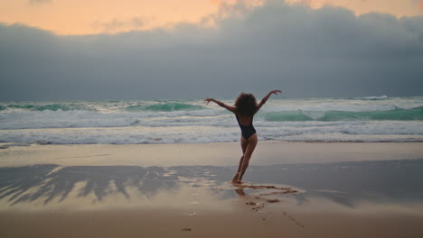 Girl-dancing-wet-sand-near-ocean-waves-cloudy-evening.-Woman-performing-dance.