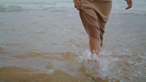 Woman-feet-walking-water-at-evening-closeup.-Unknown-lady-stepping-at-wavy-ocean