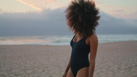 Woman-tourist-walking-beach-in-black-swimsuit-at-summer-dusk.-Girl-relaxing
