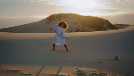 Performer-dancing-sunset-sand-dunes-wearing-white-dress.-Girl-moving-graceful.