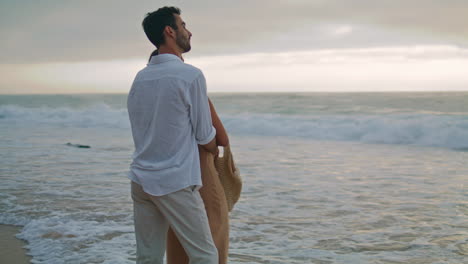 Romantic-lovers-dating-ocean-evening-beach.-Latin-man-embracing-unknown-woman