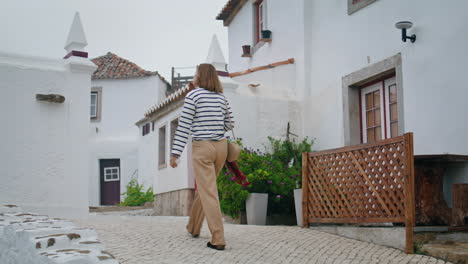 Girl-walk-mediterranean-town-with-white-wash-houses-on-summer-vacation-vertical.