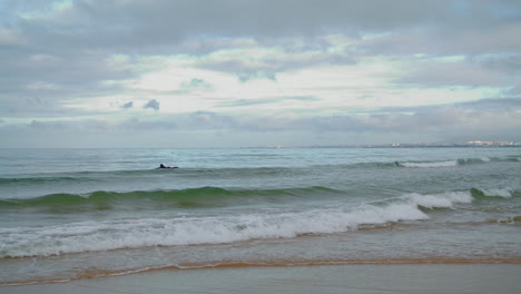 Surfer-swim-ocean-waves-on-cloudy-day-vertical-view.-Rolling-sea-water-splashing