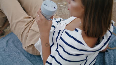 Hand-holding-reusable-coffee-cup-closeup.-Serene-girl-drinking-morning-beverage