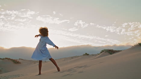 Girl-dancer-throwing-sand-performing-at-summer-sunset-on-dunes.-Woman-dancing.
