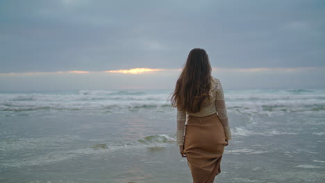 Dreamy-woman-walking-ocean-waves-closeup.-Lady-looking-sea-view-evening-vertical