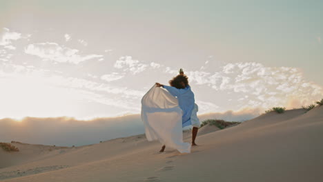 Girl-performer-dancing-fabric-fluttering-wind-at-sunset-sky-in-sand-desert.