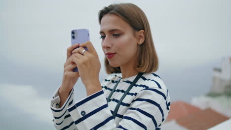 Tourist-blogger-make-photos-seaside-town-closeup.-Beautiful-girl-use-smartphone