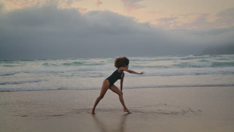 Girl-making-wheel-beach-sand-gloomy-evening.-Woman-performing-acrobatic-element.