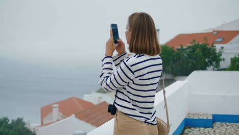 Girl-taking-smartphone-pictures-at-sea-town-vertically.-Blogger-exploring-city