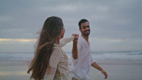 Cheerful-lovers-connecting-hands-dark-beach.-Loving-people-ocean-date-vertically