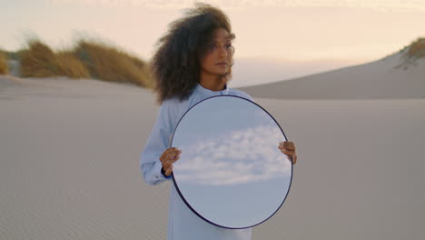 Woman-holding-mirror-sand-desert-at-summer-close-up.-Girl-standing-in-wilderness