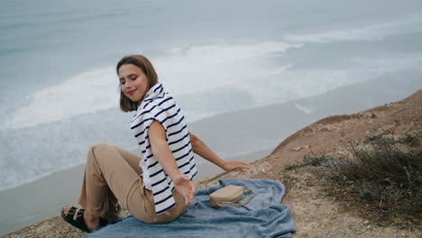 Serene-woman-resting-ocean-cliff-edge-vertical.-Smiling-tourist-looking-camera