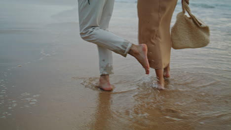 Couple-legs-crossing-seashore-at-summer-closeup.-Tender-spouses-enjoying-ocean