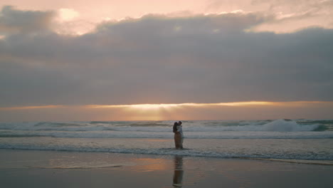 Beautiful-pair-spinning-morning-sea-beach.-Romantic-lovers-embracing-vertical