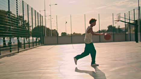 Involved-teenager-bounce-ball-at-stadium.-Basketball-player-making-basket-throw