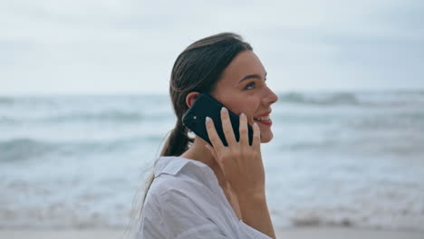 Mujer-Hablando-Por-Teléfono-Playa-Día-Nublado-De-Cerca.-Chica-Caminando-Cerca-De-Las-Olas-Del-Océano.