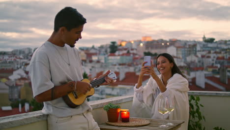 Entspannte-Liebende-Spielen-Gitarre-Auf-Der-Terrasse-Bei-Sonnenuntergang.-Romantisches-Paar-Ruht-Sich-Zusammen-Aus