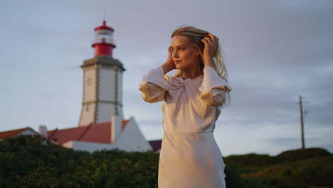 Blonde-girl-walking-lighthouse-landscape-portrait.-Woman-posing-evening-nature