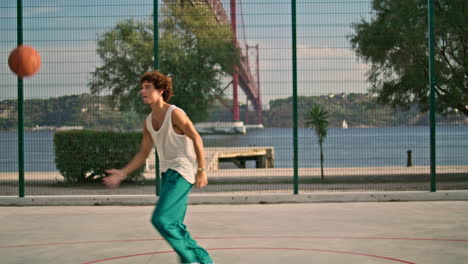 Curly-guy-playing-basketball-on-sports-field.-Teenager-throwing-ball-vertically