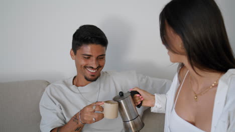 Smiling-couple-drinking-coffee-at-sofa-together-closeup.-Newlyweds-taking-break