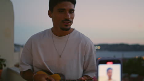Girl-hands-recording-man-guitar-playing-video-sunset-terrace.-Guy-singing-song